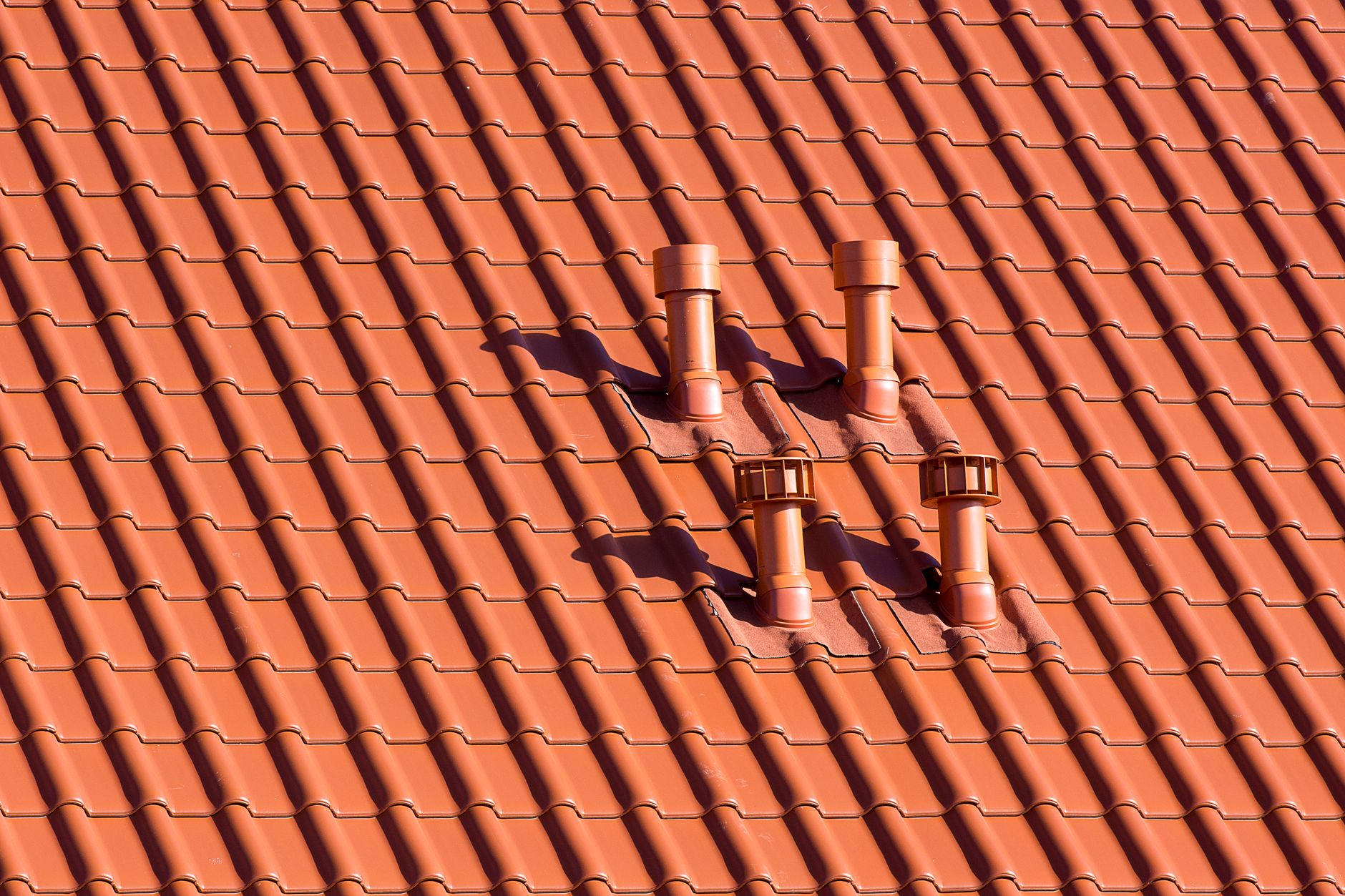 Vibrant red tiled rooftop featuring symmetrical chimneys casting soft shadows in daylight. — Locations of Asbestos in Old Bar